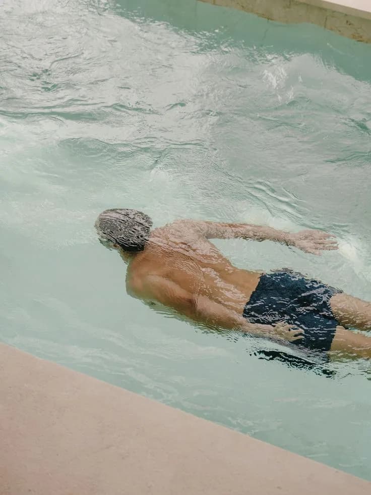A man swimming in clear pale water