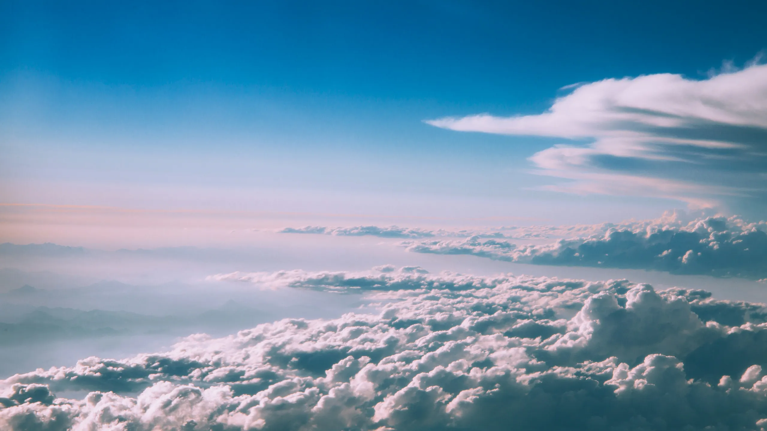 A sea of white cloud seen from above, under a soft blue sky
