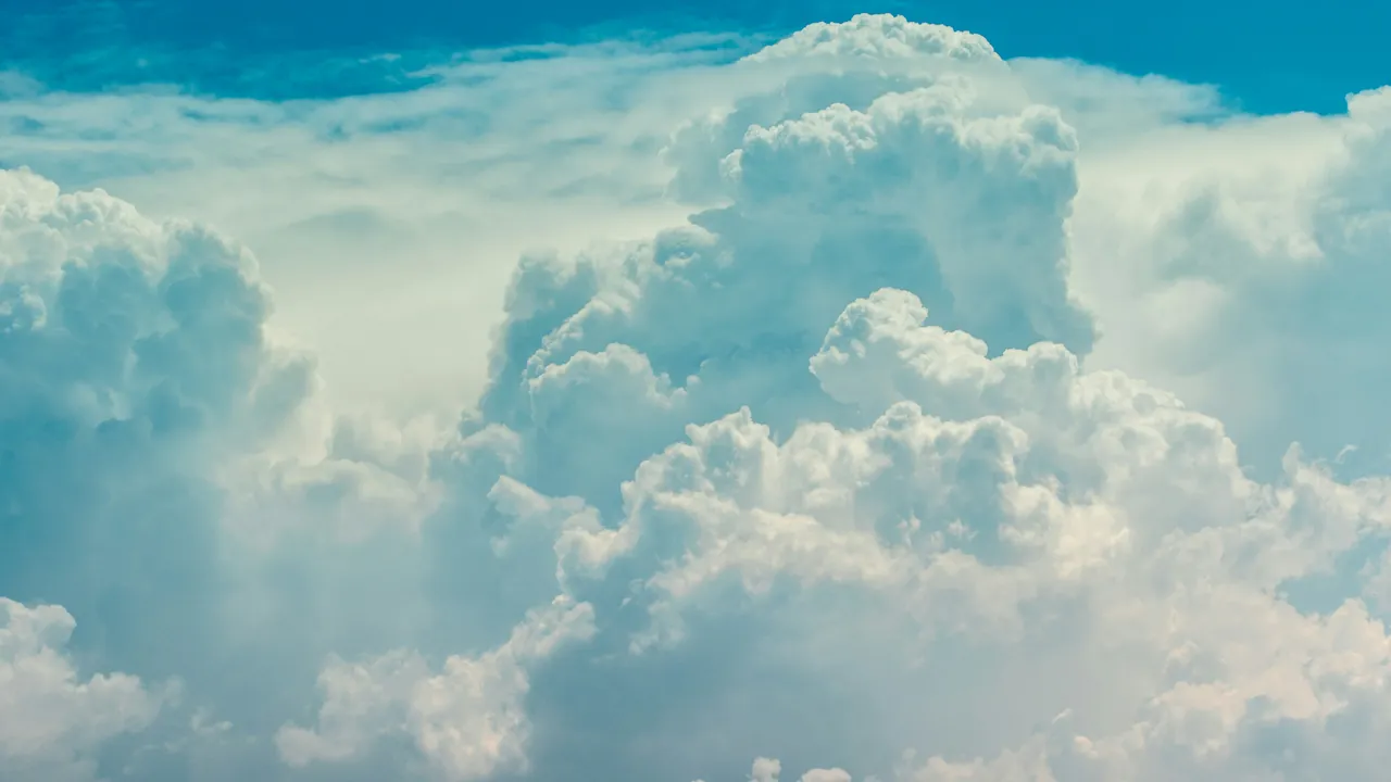 Towers of white cumulus cloud against a clear blue sky