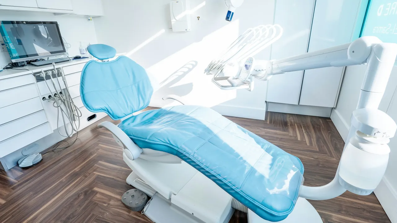 An empty pale blue dental chair in a bright, modern surgery