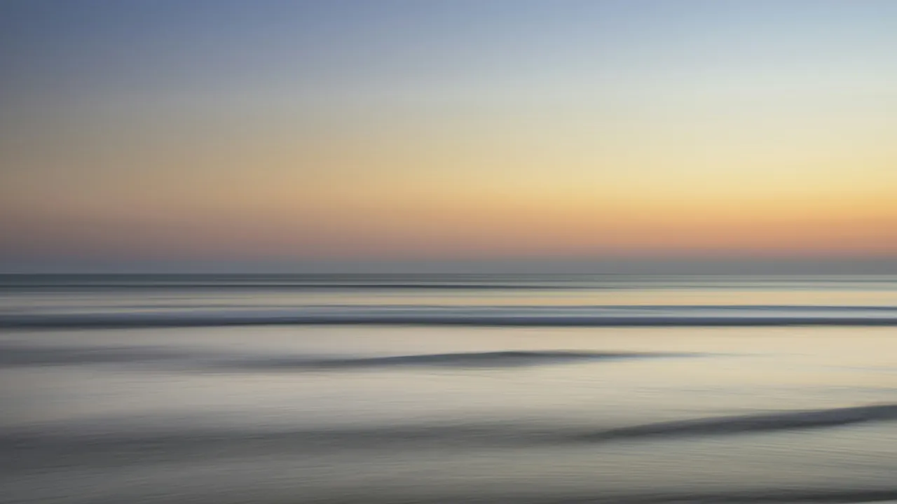 A calm sea under bands of gold and grey cloud, smoothed by a long exposure