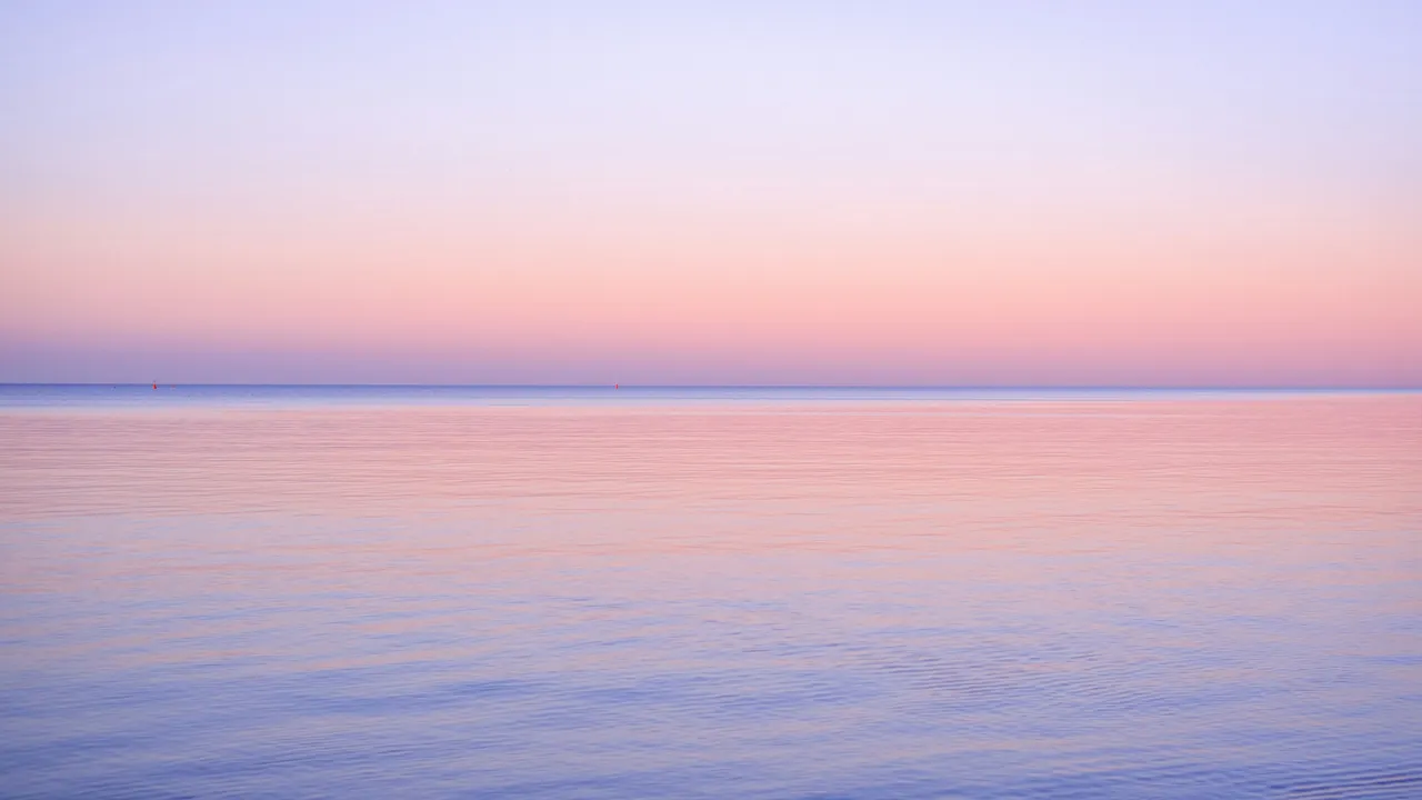 Still water reflecting a soft pink and lilac sky