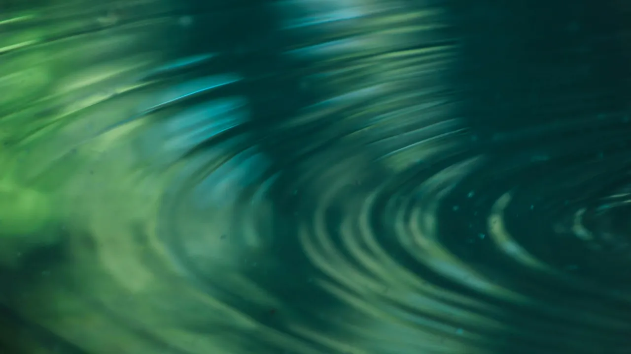 Concentric ripples moving across dark green-blue water