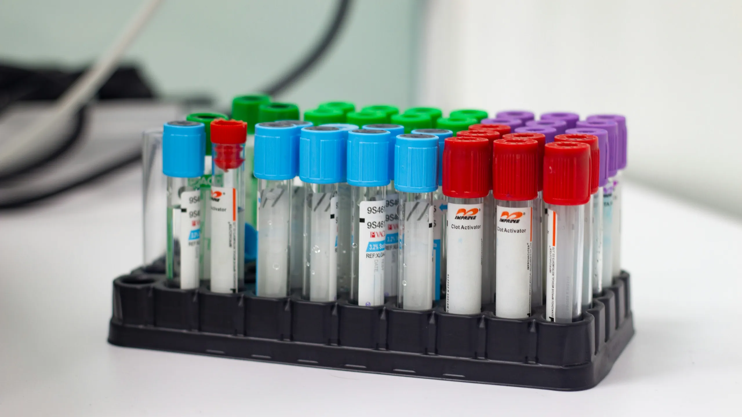 A rack of sample tubes with coloured caps on a white bench