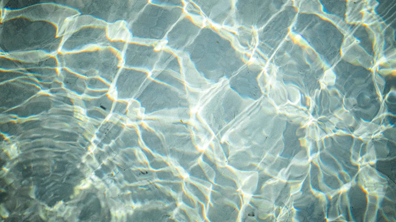 Sunlight rippling in a net of light across clear, pale water