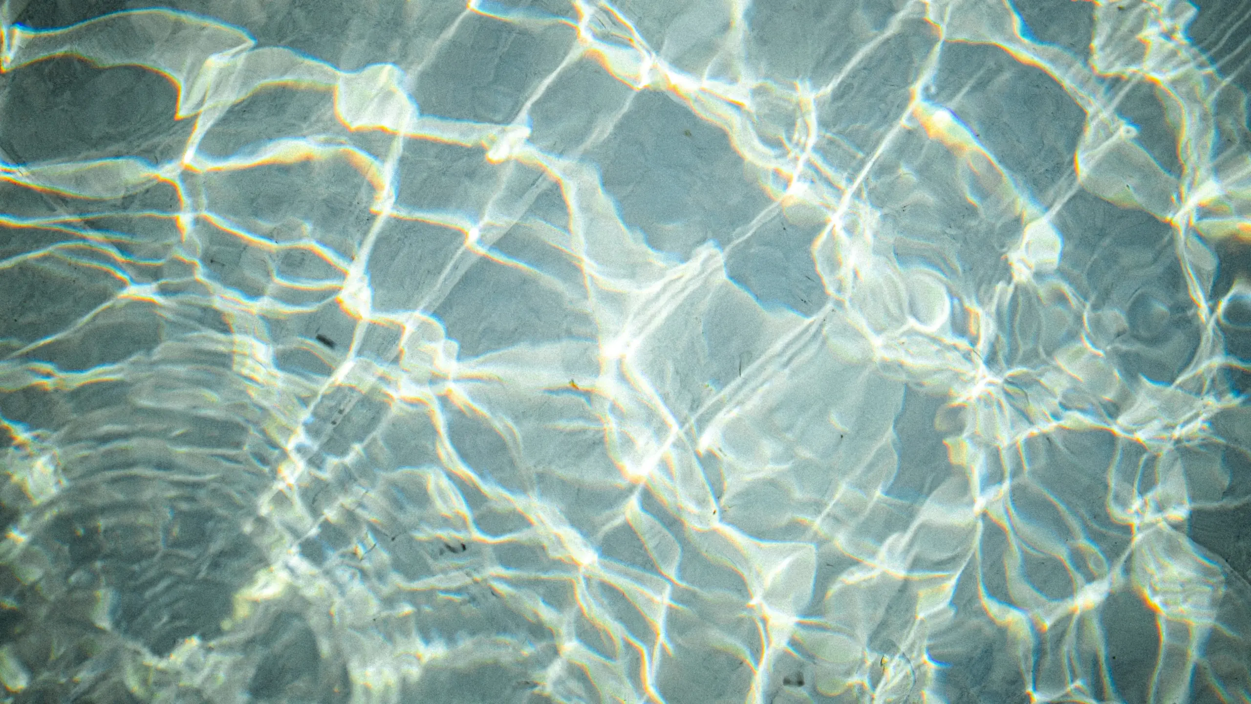 Sunlight rippling in a net of light across clear, pale water
