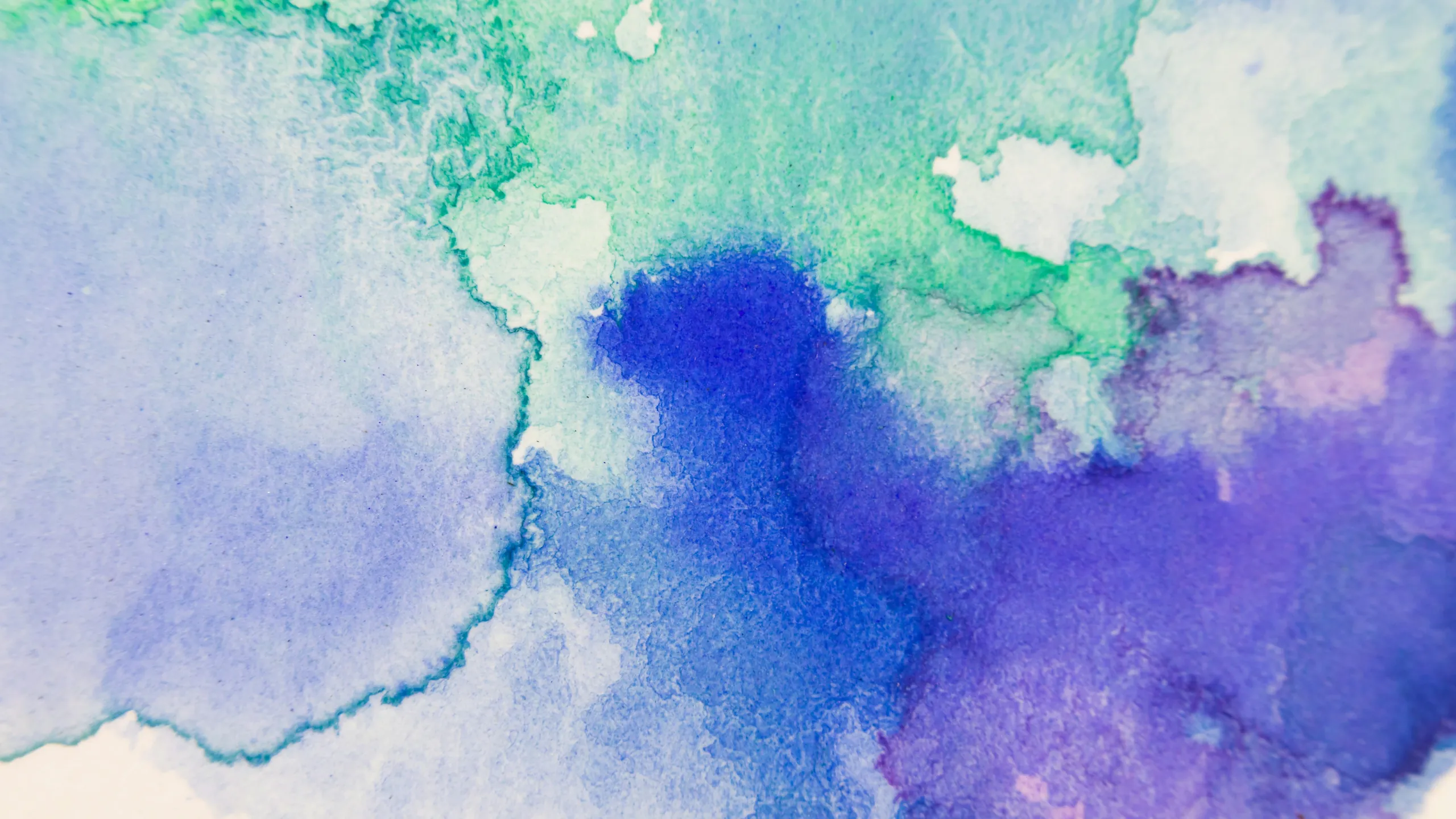 Blue, violet and green watercolour bleeding across white paper