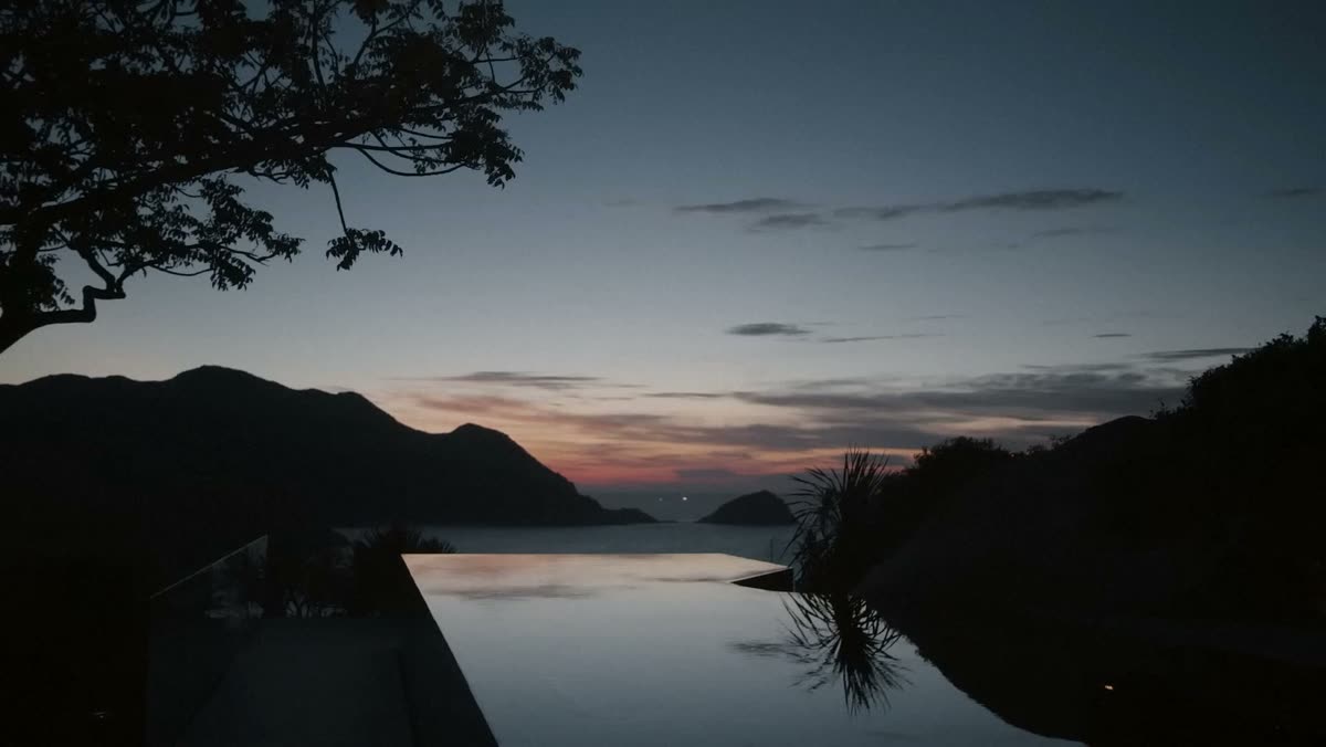 An infinity edge at dusk above a bay