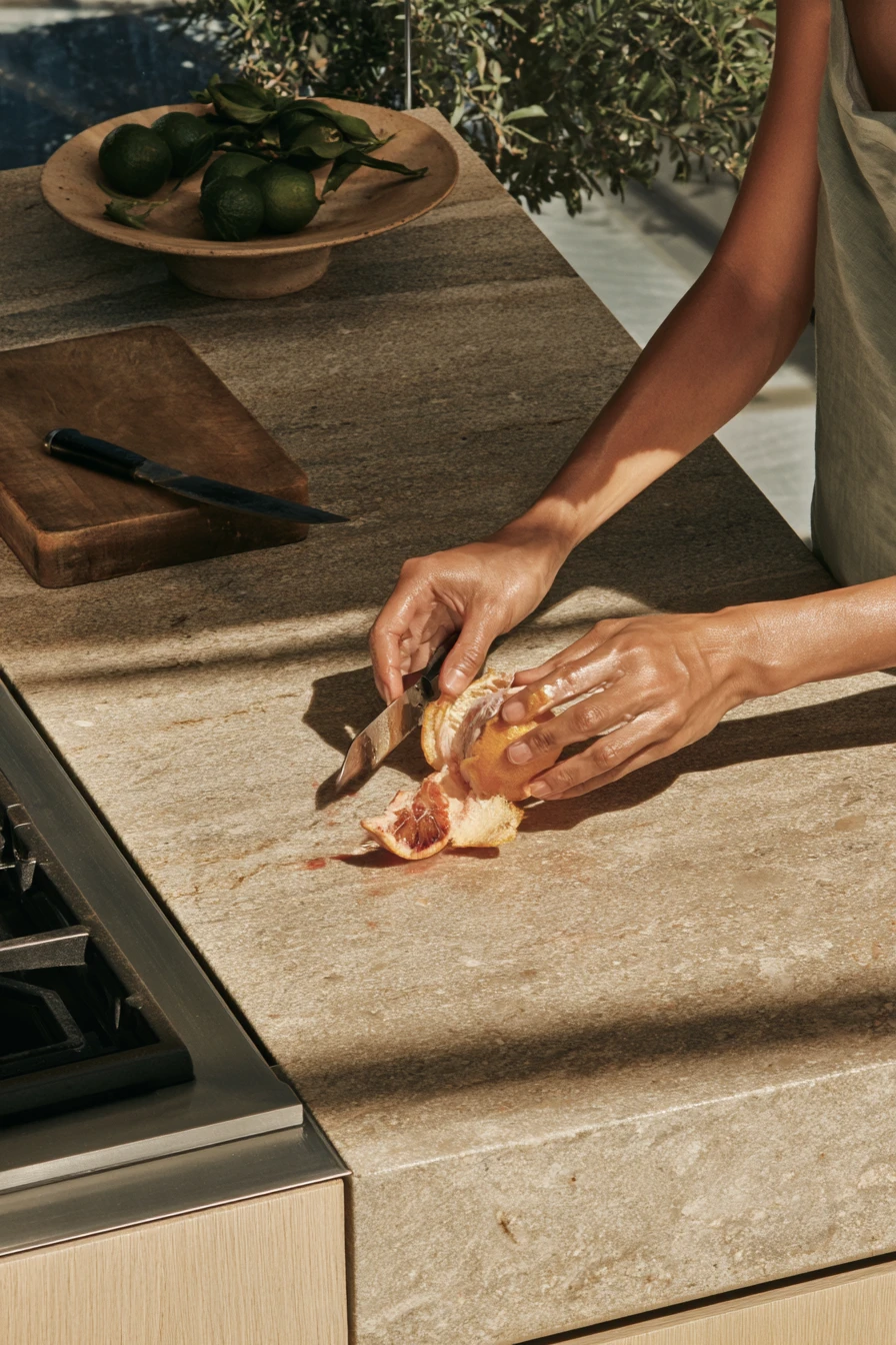 Hands peeling a blood orange on a stone counter